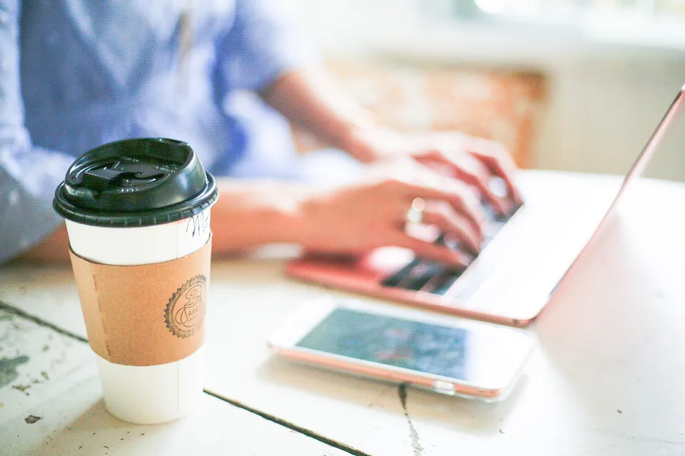 A freelancer working at a small desk with a laptop and notes