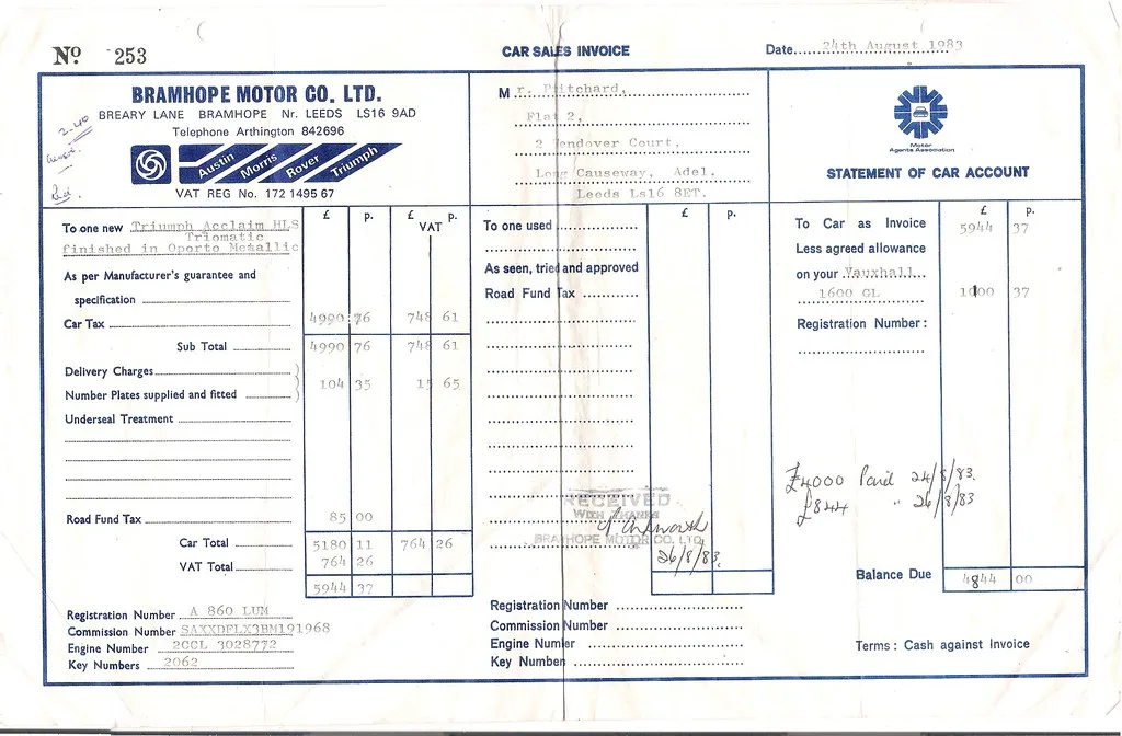 A paper invoice and a pen on a desk, next to a laptop