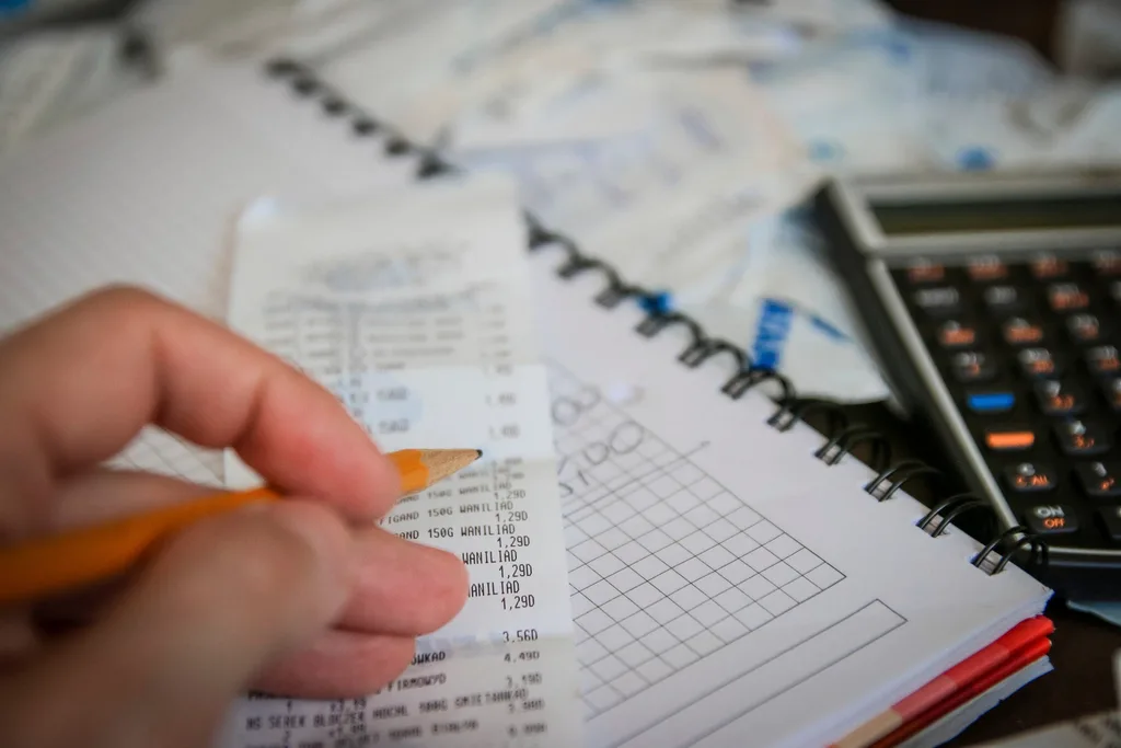 A calculator, printed figures and a notebook on a work surface
